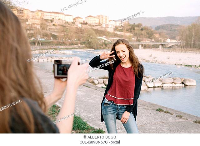 Girlfriends taking photograph by river, Belluno, Veneto, Italy