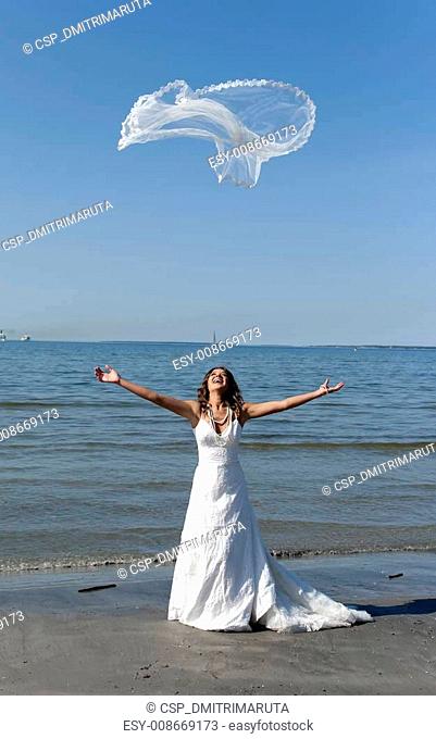 beautiful young bride throwing the veil near the sea