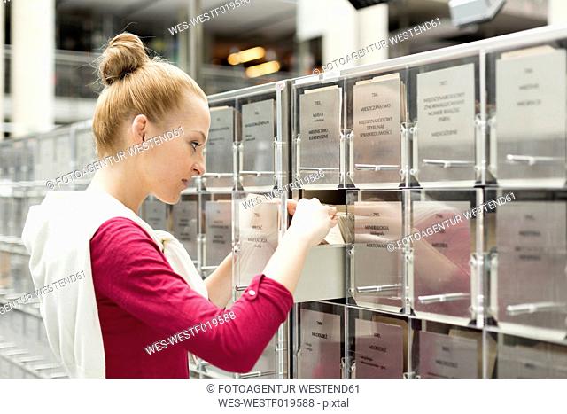 Student in a university library at filing cabinet