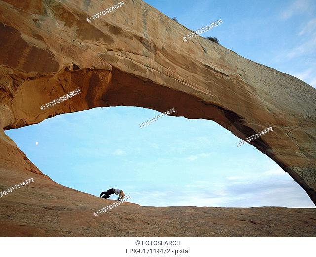 Man doing bridge under arched rock