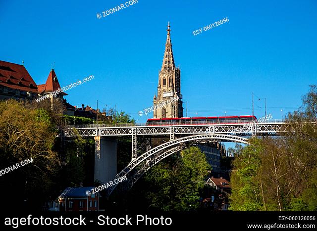 Bern, Switzerland - April 13, 2017: Train driving over Kirchenfeld Bridge with the Cathedral in the background