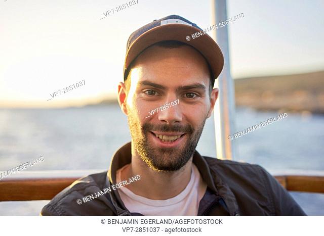 Portrait of happy smiling young French student man with cap during sunset in Malta, Europe
