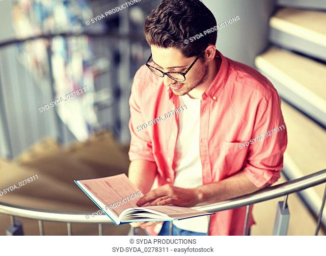 student boy or young man reading book at library
