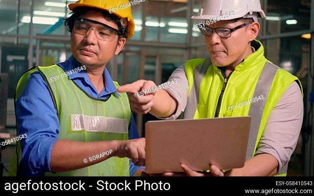 Two factory industrial workers technician or engineer and manager wear uniforms safety feeling upset with the engine machine of the factory arguing about...