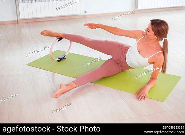 Exercises with pilates ring. Woman doing aerobics workout at sport gym with panoramic windows