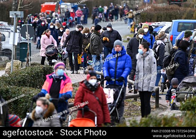 08 March 2021, Hessen, Kronberg: Families queue up in front of the entrance to the Opel Zoo before its reopening. The extensive measures to protect against...