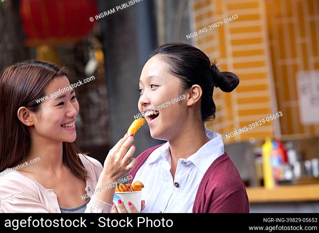 Two Young Women Eating Snacks