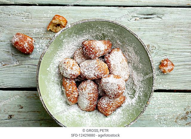 A plate of homemade, deep-fried pastries with icing sugar (seen from above)