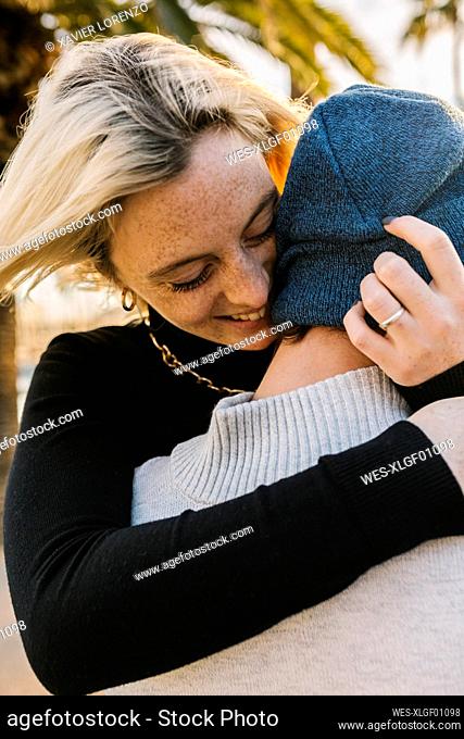 Cheerful young woman embracing boyfriend with arms around