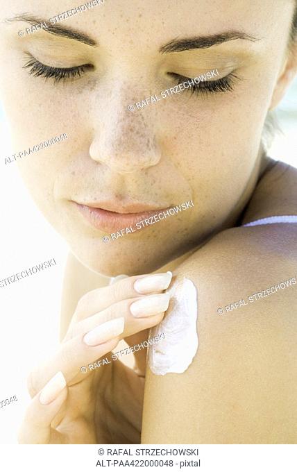 Woman applying sunscreen to shoulder, close-up