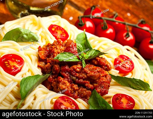 Closeup of delicious spaghetti Bolognaise or Bolognese with savory minced beef and tomato sauce garnished with parmesan cheese and basil