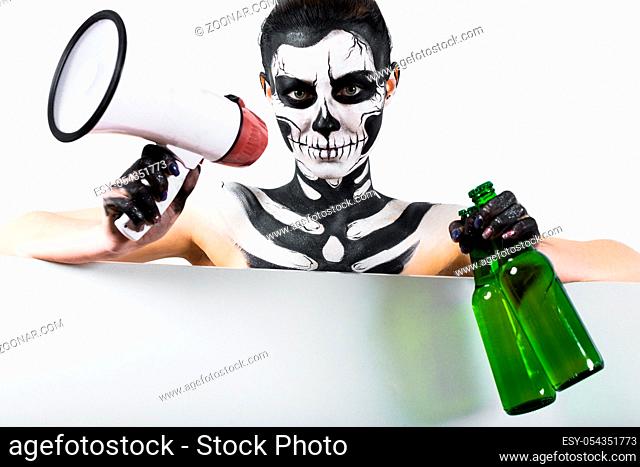 Isolated on white, closeup picture, young brunette caucasian pretty woman with scull body art holds green beer bottles and megaphone, grey eyes, languid look