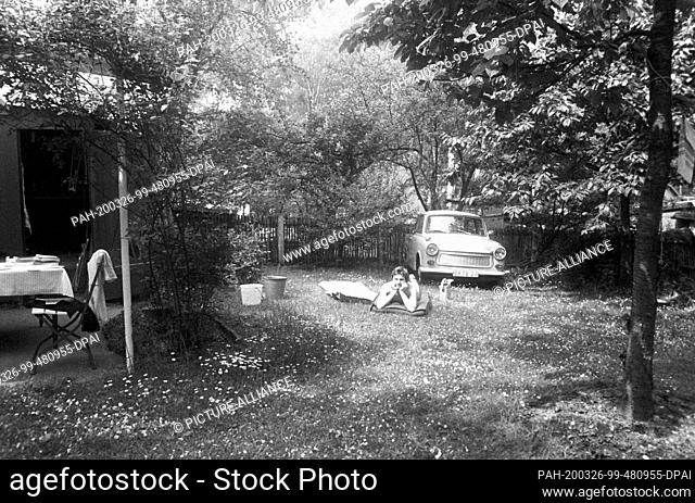 30 November 1978, Saxony, Leipzig: A young Masnn lies in a meadow in his garden in front of his Trabant, in the late 1970s