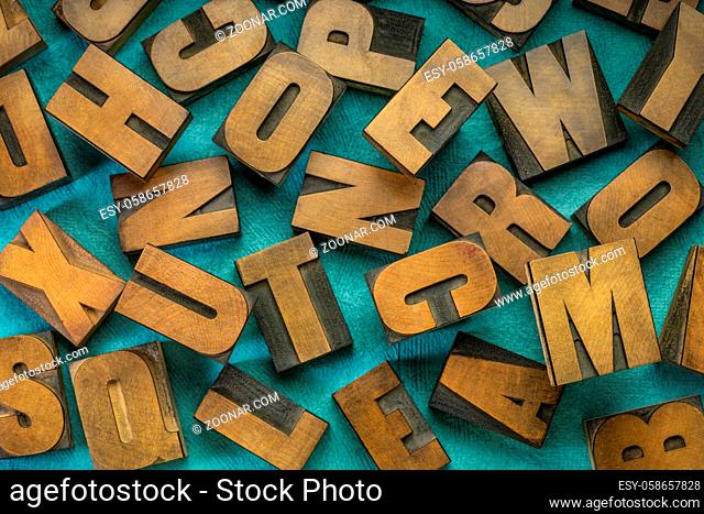 random letters overhead background - vintage letterpress wood type (inverted image) against turquoise handmade bark paper