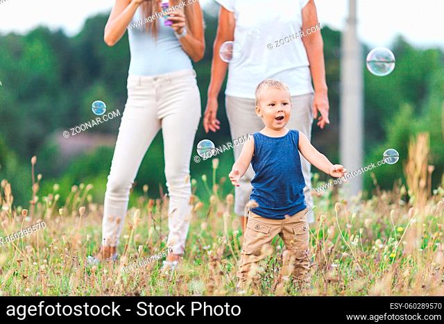 Happy child with family having a great time blowing bubbles outdoors