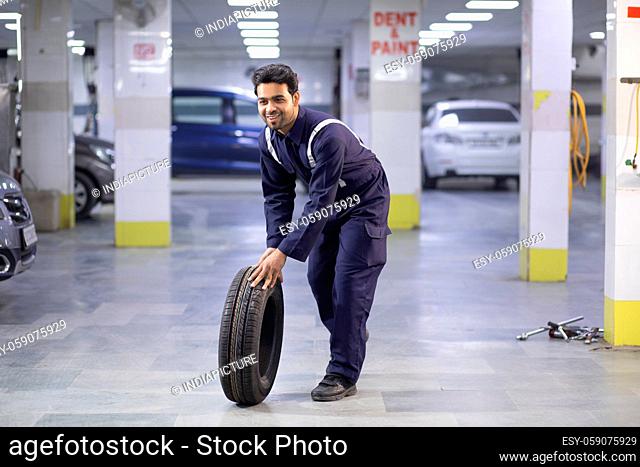 Technician rolling a new tyre in a workshop, during repairs