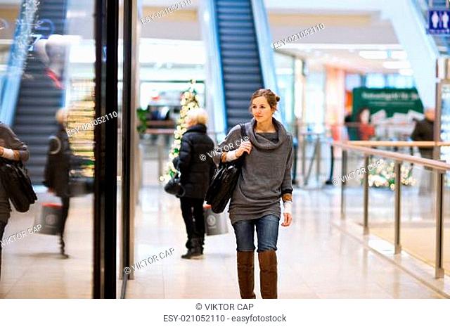 Young woman looking at store windows when shopping