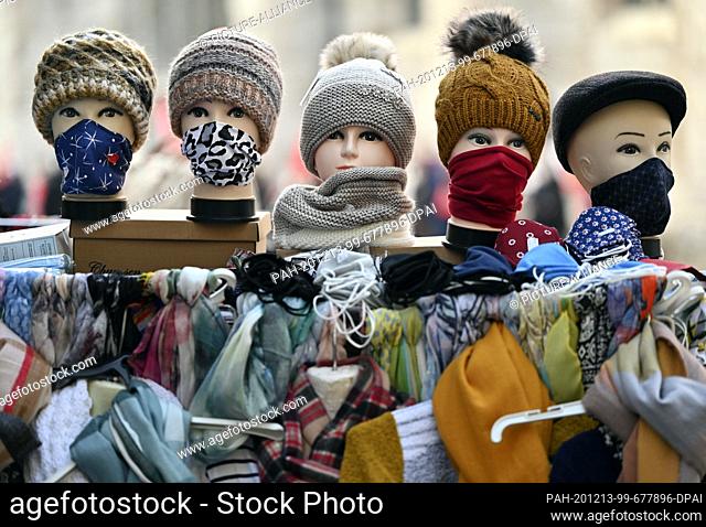 08 December 2020, Thuringia, Mühlhausen: Mannequin heads with face masks, scarves and caps are standing in front of a clothing shop in the old town