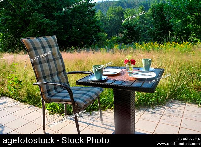 Breakfast on the terrace in front of green nature on a beautiful summer day