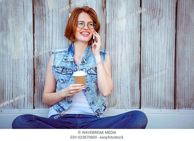 smiling hipster woman holding a coffee making a phonecall