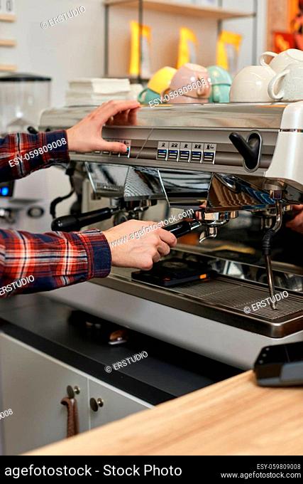 Barista using a coffee machine to make coffee in cafe