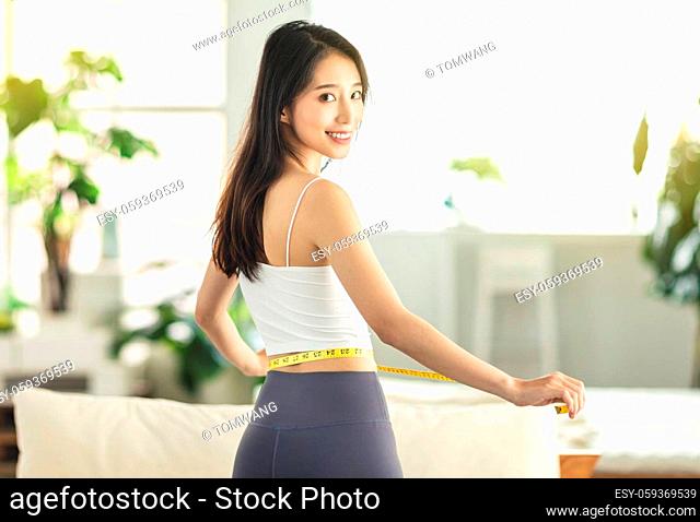 young woman holding a measuring ruler while dancing, turning around, very satisfied with her posture, very happy to lose weight