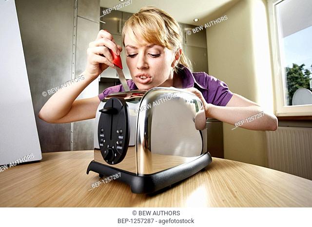 Girl holding a knife in the toaster