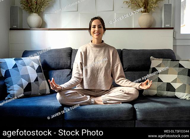 Smiling young woman meditating at home