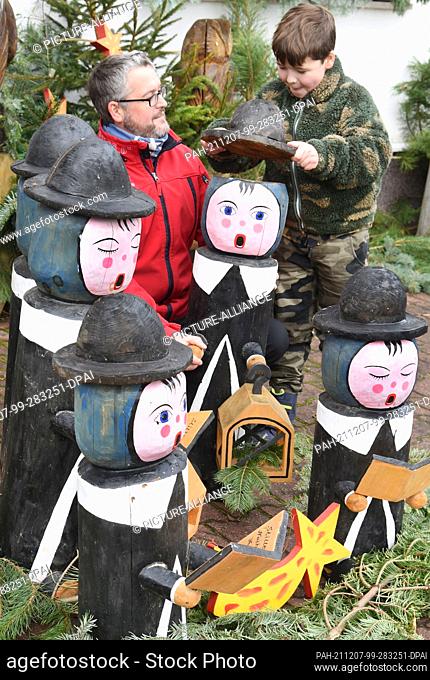 05 December 2021, Saxony, Borsdorf: In the case of the carol singers who decorate the Pfaff families' front garden, 8-year-old Felix and his father Denny Pfaff...
