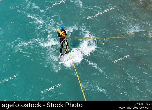 Maienfeld, GR / Switzerland - 4. August 2019: man wakeboard surfing on a river with a rope tied to a bridge