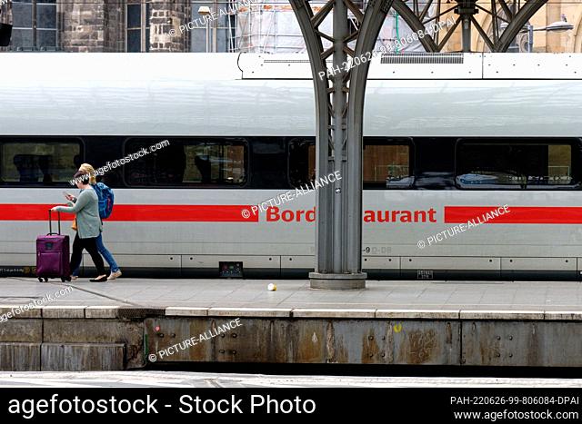 26 June 2022, North Rhine-Westphalia, Cologne: Travelers board a Deutsche Bahn ICE train on a platform at the main station