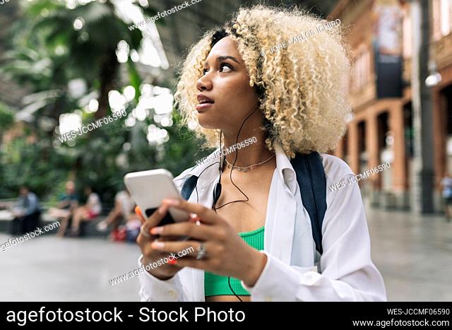 Young woman looking away holding smart phone