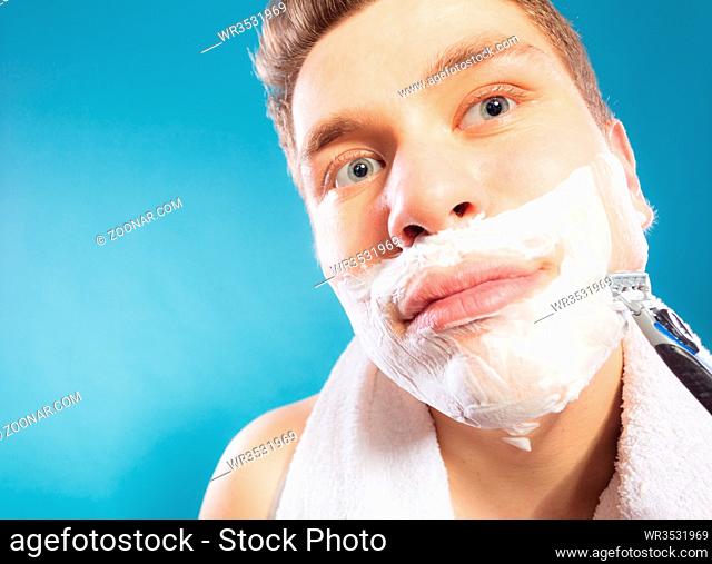 Man shaving using razor with cream foam. Handsome guy removing face beard hair. Skin care and hygiene