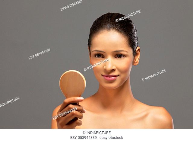 Close-up of beautiful young woman with a hand mirror