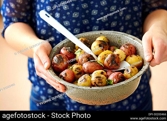 Close-up of Woman's Hands Holding Bowl of Grilled Red and White Baby Potatoes