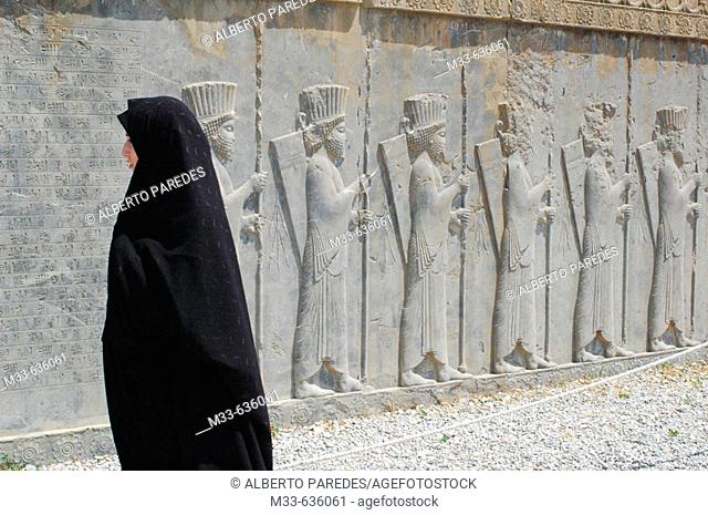 Warriors reliefs and woman in chador. Persepolis (Takht-e Jamshid). Fars. Iran