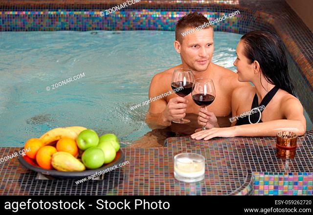 Young couple enjoying relaxation in spa with glass of wine