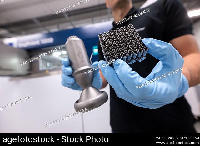 PRODUCTION - 30 November 2022, Baden-Wuerttemberg, Ditzingen: An employee of laser specialist Trumpf shows the cutaway model of a thruster for satellites and...