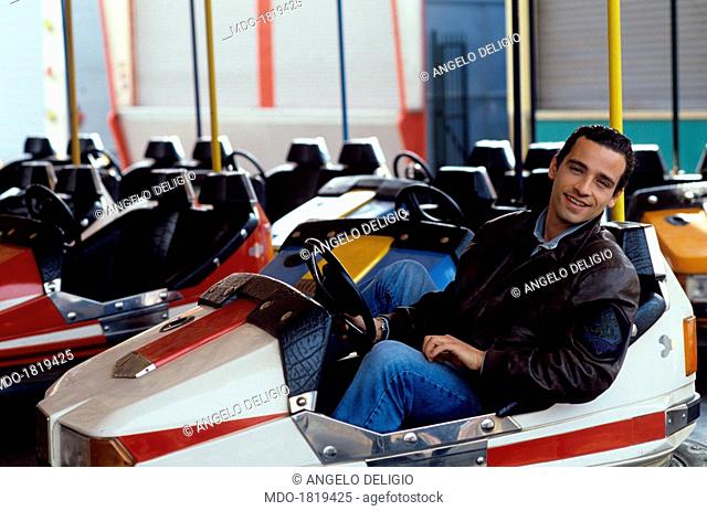 Italian singer-songwriter Eros Ramazzotti having fun on a bumper car. Italy, 1990