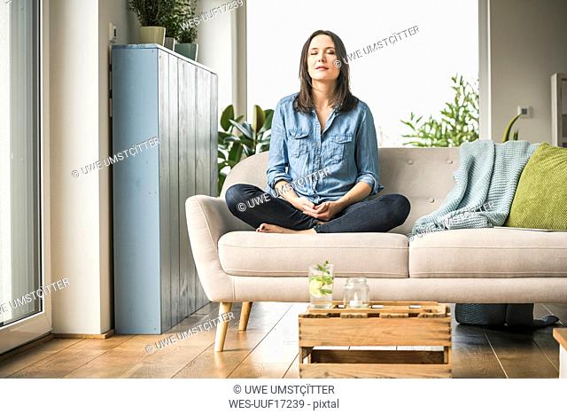 Woman sitting on the couch at home with closed eyes