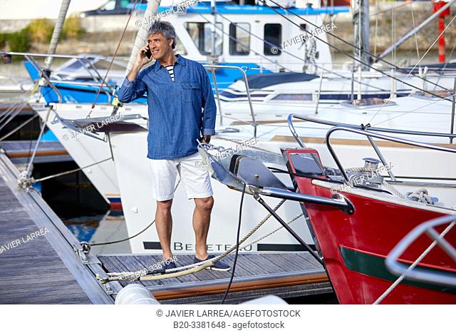 Man in the harbor, talking on phone. Port De Plaisance Larraldenia, Ciboure, Aquitaine, Basque Country, France