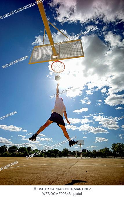 Man playing basketball on yellow court, dunking
