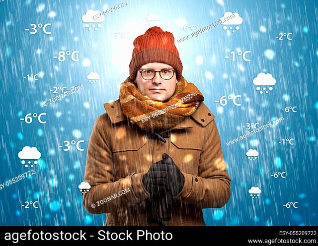 Young man freezing in warm clothing with weather condition and forecast concept