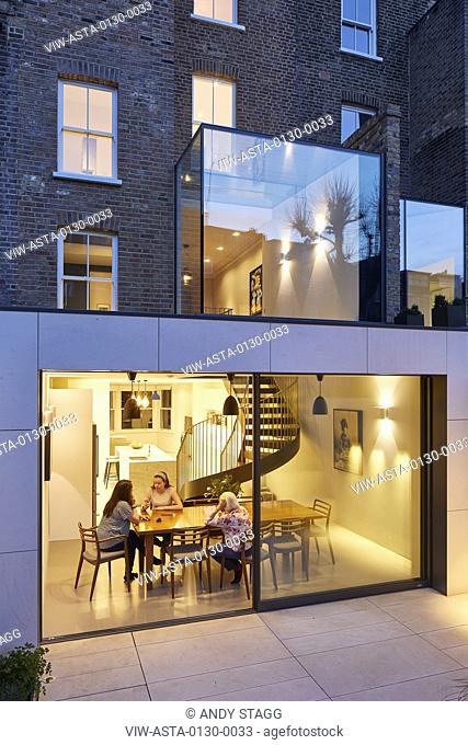 View from garden with sunken patio and dining area at dusk. Aynhoe House, London, United Kingdom. Architect: Paul Archer Design - Architects & Design, 2018