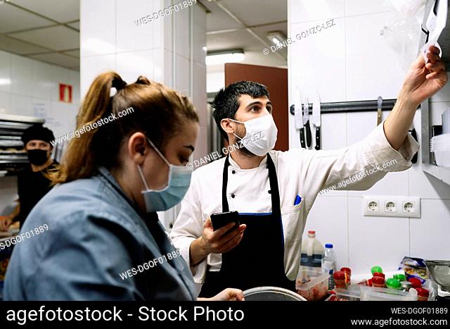 Male and female chef working in commercial kitchen during COVID-19