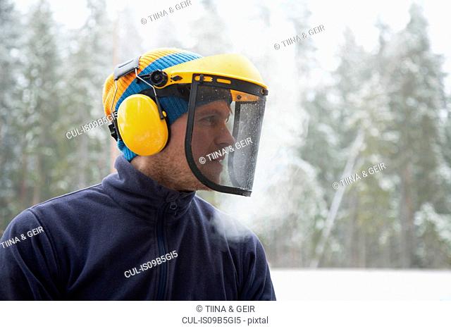 Logger wearing safety visor in forest, Tammela, Forssa, Finland