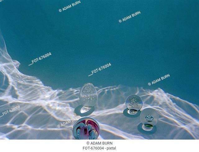 Four glass paperweights sitting at the bottom of a swimming pool