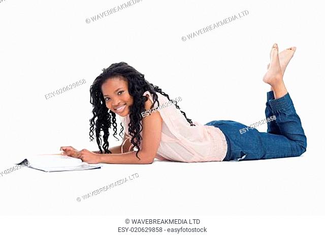 A woman lying on the floor smiling at the camera with a magazine in front of her