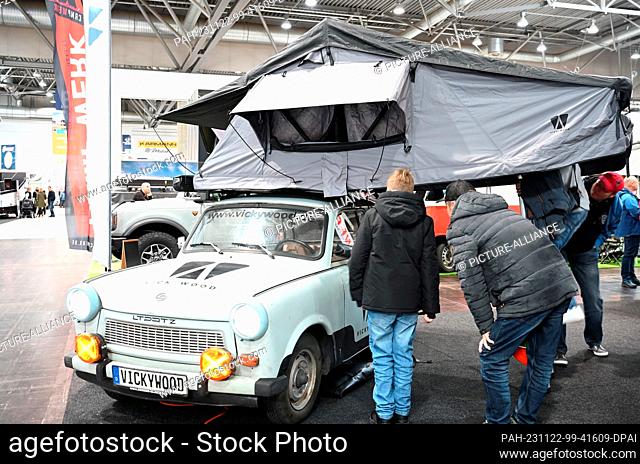 22 de noviembre de 2023, Sajonia, Leipzig: Visitantes de la feria ""Touristik " Caravaning International 2023"" mira una tienda de techo en un Trabant