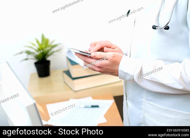 A female doctor texting on smartphone in medical office